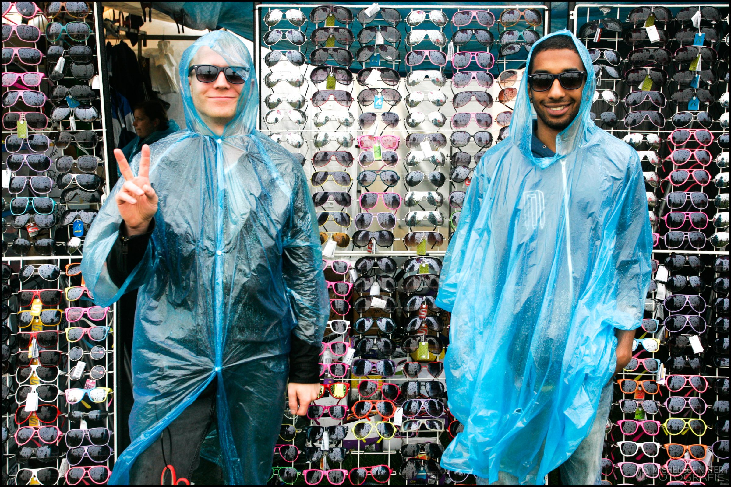 twee mannen in de regen met regencape en zonnebril op proberen brillen te verkopen tijdens regenachtig festival foto gemaakt door Michel Schnater