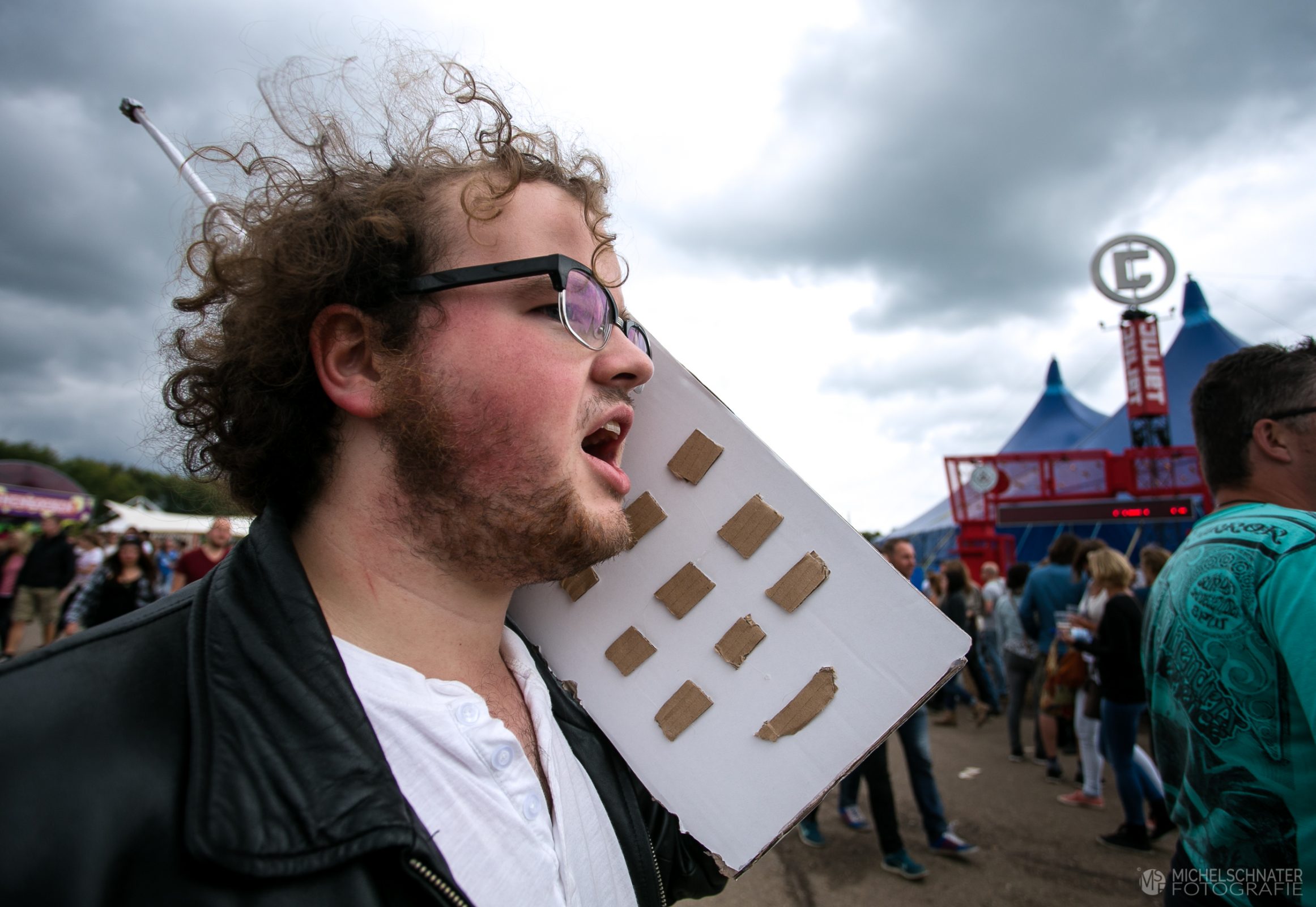 Jonge man loopt op Lowlands festival met kartonnen grote telefoon die hij zelf heeft gemaakt foto gemaakt door Michel Schnater
